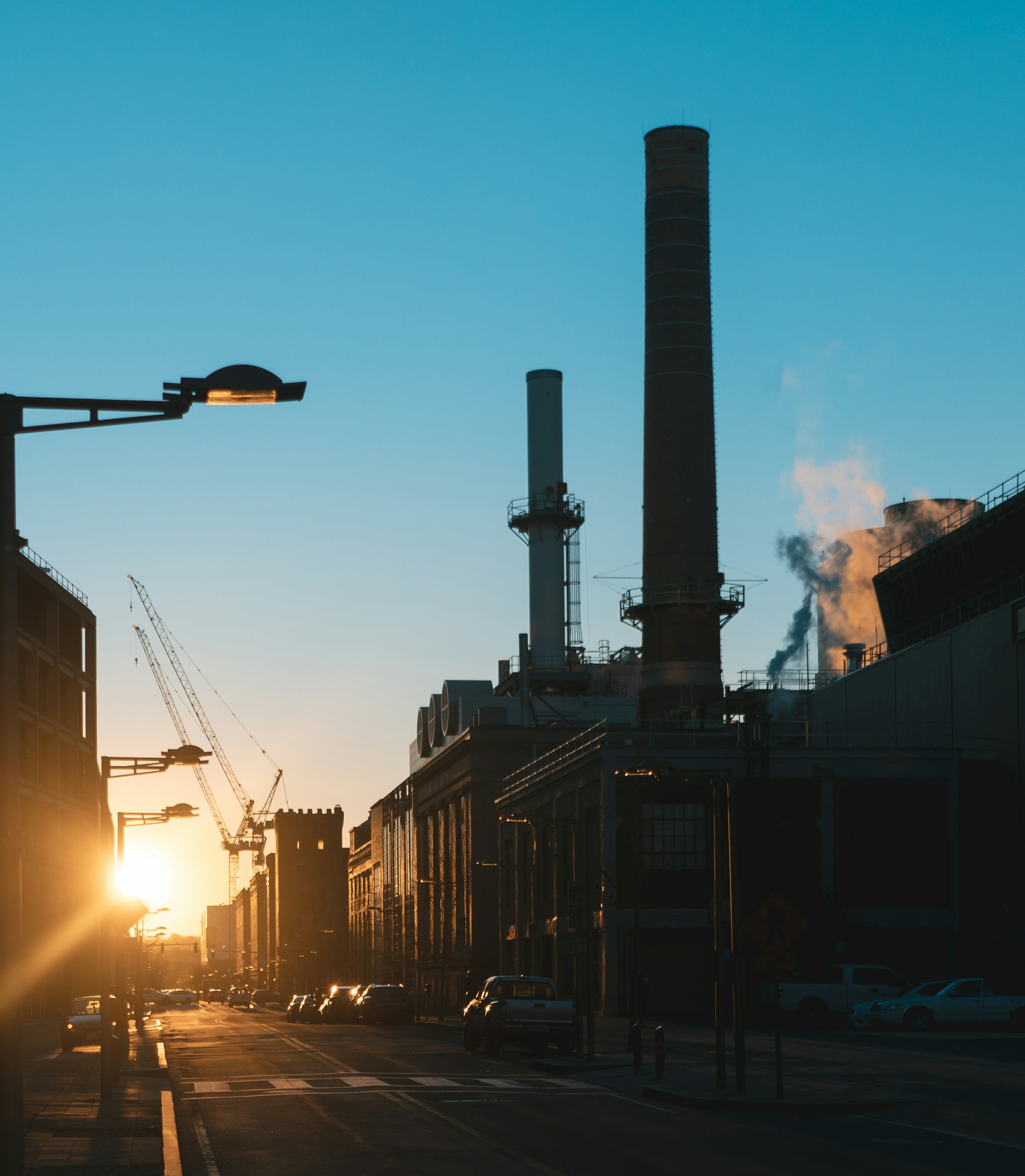 Les cheminées d'une centrale en bord de rue, au soleil couchant